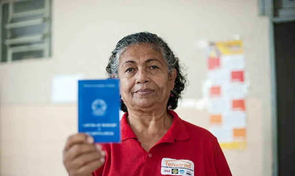 Trabalhadora doméstica com a carteira de trabalho em mãos. Mesmo com leis específicas e 10 anos da PEC das Domésticas, mais da metade da categoria ainda vive na informalidade. Foto: Carol Melo/Fenatrad